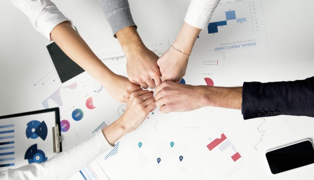 pexels-photo-5716037-5716037 Colleagues celebrate success with a fist bump over financial charts depicting teamwork and unity.